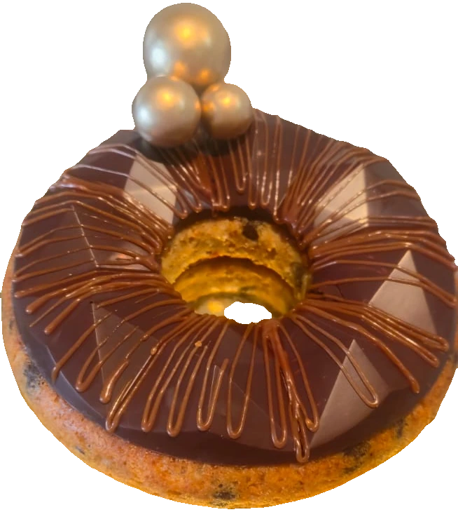A ring cake with chocolate glaze, a caramel drizzle and gold spheres
